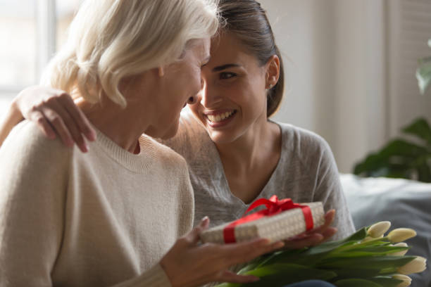 istock Grown up daughter makes present to middle aged mother 1208113575