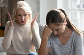 Middle aged mother scolding grown up daughter having difficult relationships