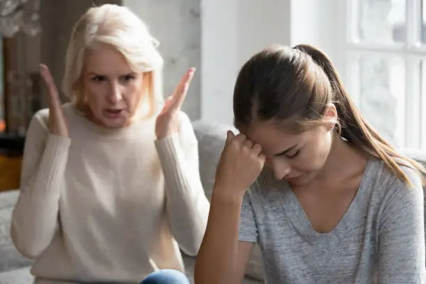 Photo of Middle aged mother scolding grown up daughter having difficult relationships