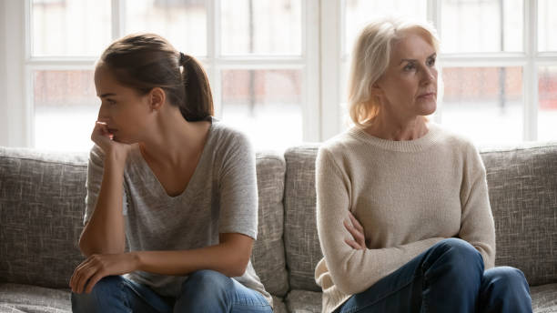 Elderly mother and grown up daughter sit on couch separately In quarrel elderly mother grown up daughter sit on couch separately having conflict, intergenerational misunderstanding, adult grandchild grandma difficult bad relations different generations concept arguing stock pictures, royalty-free photos & images