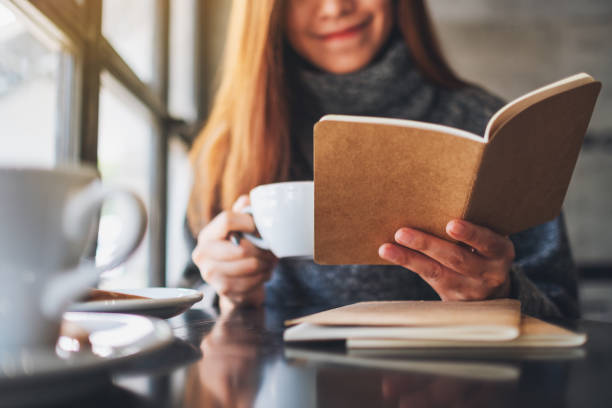 istock a beautiful asian woman reading a book while drinking coffee in cafe 1208114979