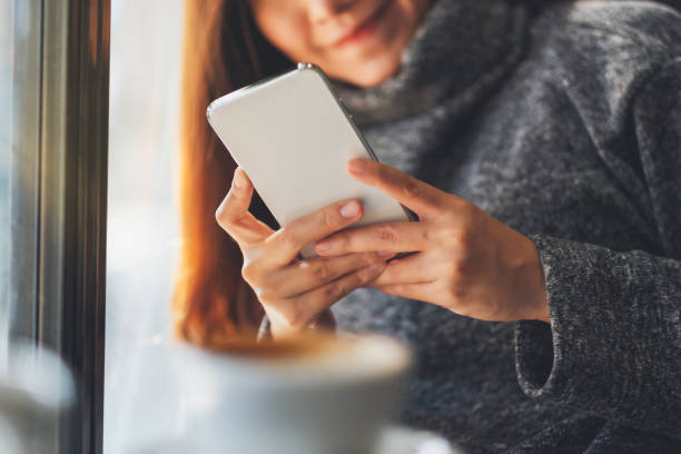 istock a woman holding and using mobile phone with coffee cup on the table in cafe 1208114981