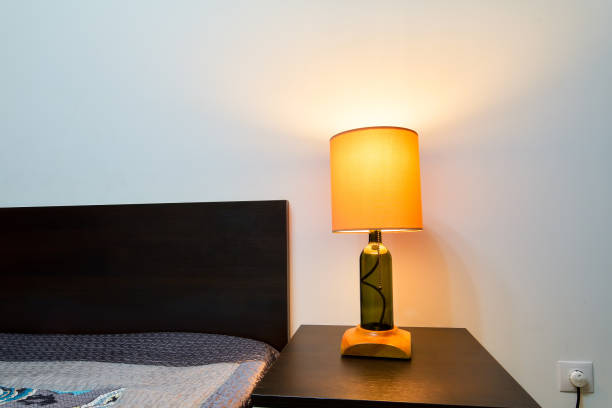 istock Lamp on a night table next to a bed 1208115422