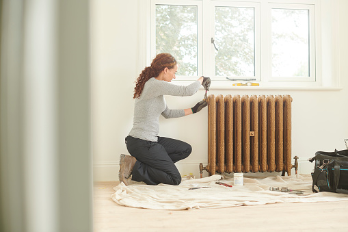 female plumber installing cast iron radiator