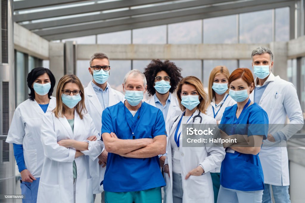 Group of doctors with face masks looking at camera, corona virus concept. A group of doctors with face masks looking at camera, corona virus concept. Doctor Stock Photo