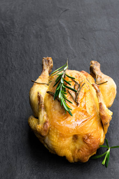 istock Roasted poussin with rosemary on black stone background 1208116832