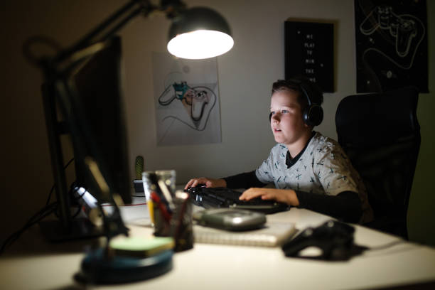 istock Carefree boy browsing the internet on his computer in late hours 1208117666