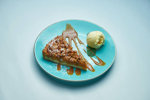 istock Appetizing pumpkin pie with caramel and vanilla ice cream on a blue plate isolated on grey background. Delicious pastries 1208123750