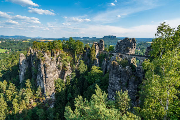 bad schandau en la suiza bohemia. puente bastei y vistas a la montaña. roca estrecha, arco de arenisca natural en europa." nhill paisaje con vegetación, cielo azul y la luz del sol. - elbe valley fotografías e imágenes de stock