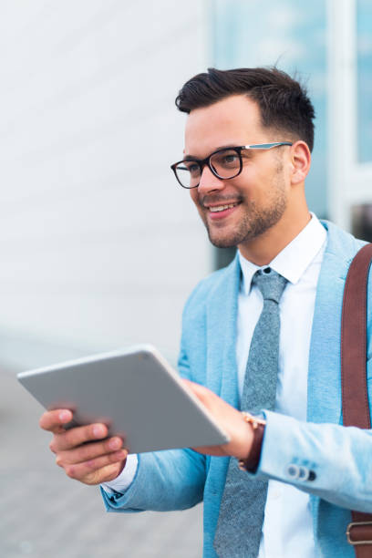 istock Businessman standing on the street smiling while holding tablet. 1208124408