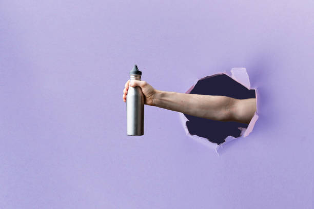 istock person hand holding a reusable zero waste material supplies, through a torn hole in paper 1208132984