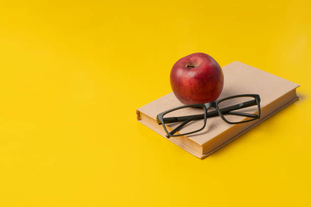 istock a stack of books, red apple and glasses isolated on colorful surface, simple abstract study concept 1208133037