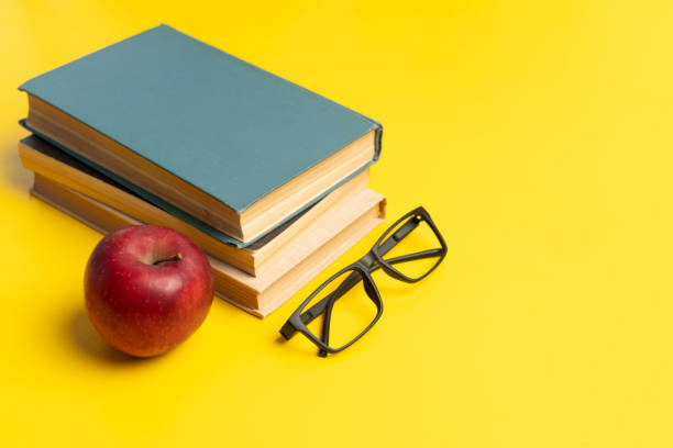 istock a stack of books, red apple and glasses isolated on colorful surface, simple abstract study concept 1208133047