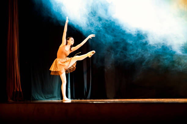 istock Young girl dancing ballet on a dark stage with blue smoke 1208134383