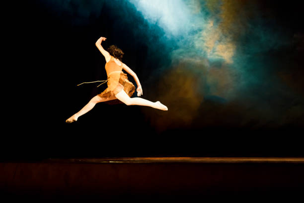 Young girl dancing ballet on a dark stage with blue smoke. Canon Mark IV.