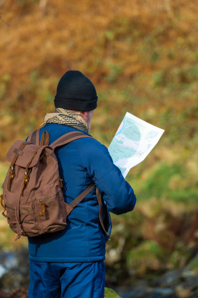 istock Active senior man looking at a map while standing beside a small stream in rural Scotland 1208136271