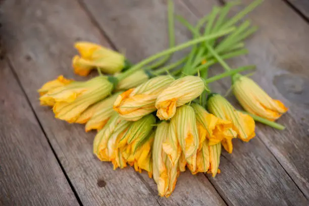 Photo of bouquet of Many yellow pumpkin flowers lie on a wooden background