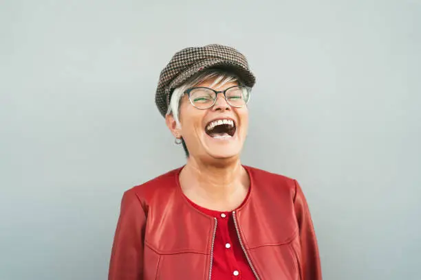 Photo of Happy senior woman laughing outdoor - Trendy mature person having fun during retired time - Elderly people lifestyle concept