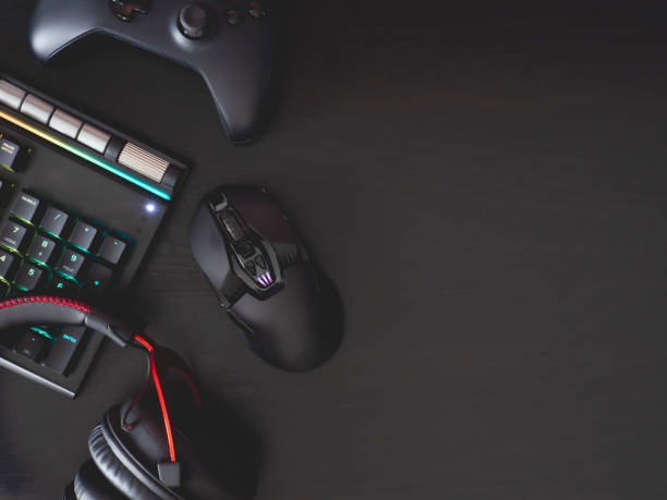 gamer work space concept, top view a gaming gear, mouse, keyboard, joystick, headset, mobile joystick, in ear headphone and mouse pad on black table background.