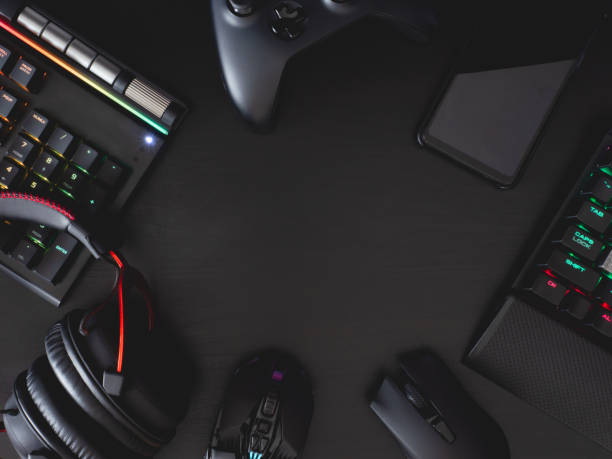 gamer work space concept, top view a gaming gear, mouse, keyboard, joystick, headset, mobile joystick, in ear headphone and mouse pad on black table background. stock photo