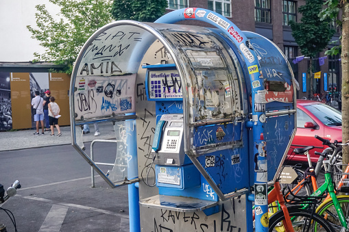 Berlin, Germany - July 30, 2018: City payphone full of graffiti