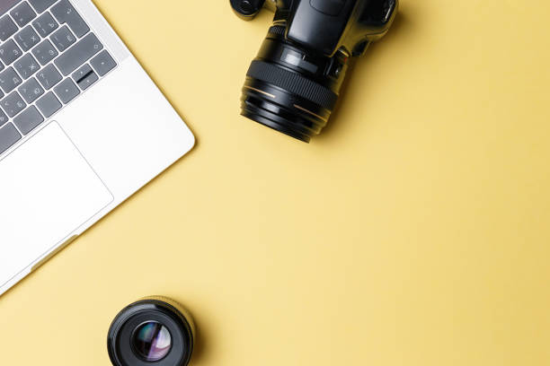 istock Photographer's workplace on a yellow background. Modern laptop, digital camera, lens, battery, smartphone. Minimalism. Top view. Copy space. Equipment for the photographer. The concept of freelancing 1208149916