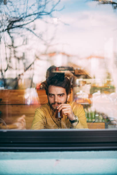 istock Handsome Man Sitting in Cafe Behind Glass 1208150287