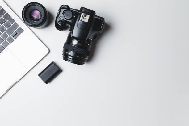 istock Photographer's workplace on a white background. Modern laptop, digital camera, lens, battery, smartphone. Minimalism. Top view. Copy space. Equipment for the photographer. The concept of freelancing 1208154401