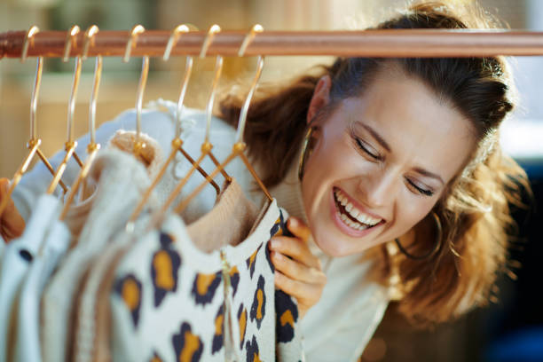 istock cheerful young woman choosing sweaters hanging on clothes rack 1208154631