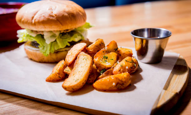 istock Tasty cheeseburger and chips on the wooden table. Restaurant. 1208154829