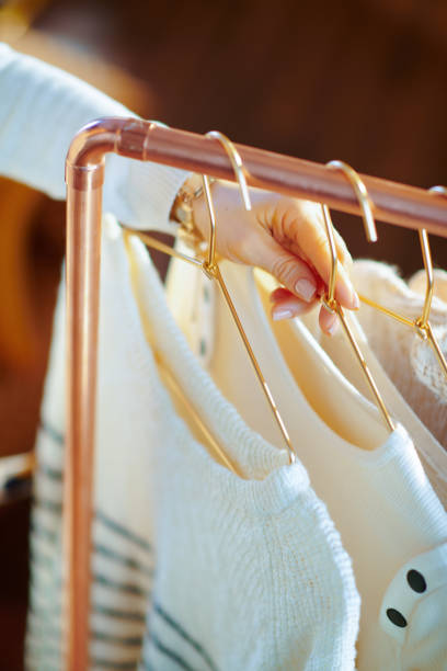 istock Closeup on elegant woman taking sweaters on hanger from rack 1208156070