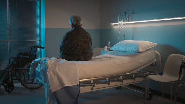 Depressed senior sitting on the hospital bed alone Depressed senior man sitting on the hospital bed alone at night, he feels lonely and abandoned night hospital bed stock pictures, royalty-free photos & images