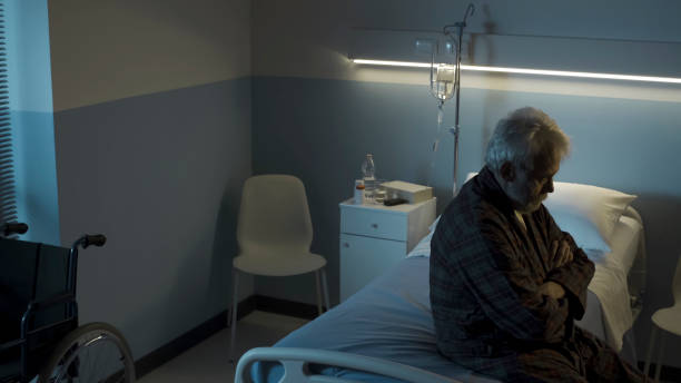Depressed senior sitting on the hospital bed alone Depressed senior man sitting on the hospital bed alone at night, he feels lonely and sad night hospital bed stock pictures, royalty-free photos & images