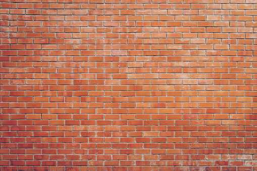 Rustic brick wall with terracotta bricks and cement grout.