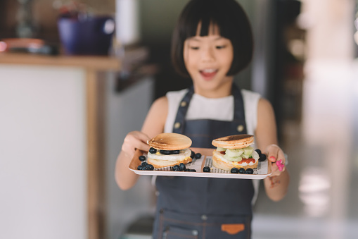 an asian chinese young girl with her pancake with blueberry served on tray breakfast standing in front of camera