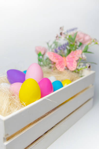 istock Colored Easter eggs and flowers in wooden white box with pink butterfly  on white background . 1208157784