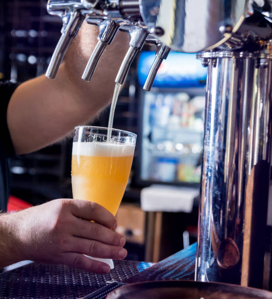 istock Bartender pouring draft beer at glasses in the bar. Restaurant. 1208158998