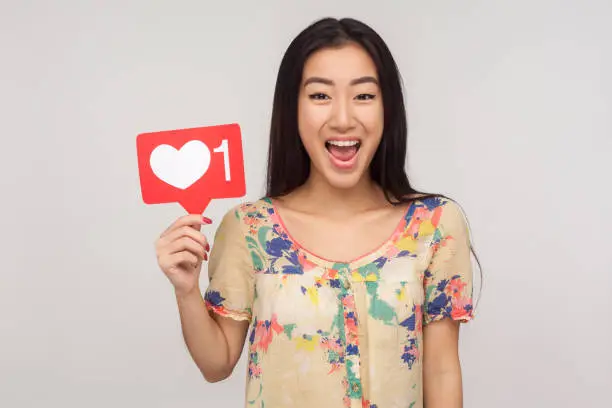 Photo of Like social media content! Delighted enthusiastic girl in blouse showing internet heart icon, recommending to subscribe