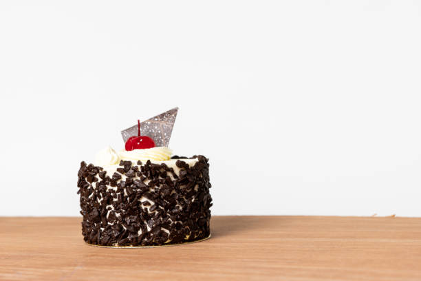 istock Chocolate cake with chocolate ship and white cream on brown table white background. 1208161947