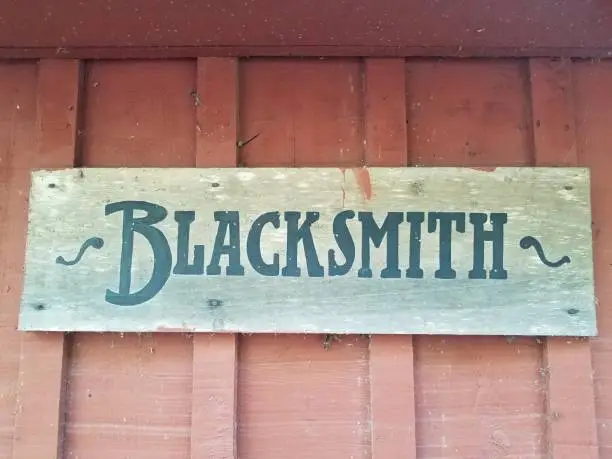 wooden blacksmith sign on dirty red wall