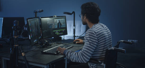 Wheelchaired film editor working on a movie Medium shot of a wheelchaired film editor working on a movie post production house stock pictures, royalty-free photos & images