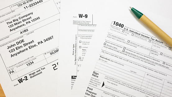 IRS 1040, W-2 and W-9 tax return form and Green Pen. Wage and tax statement concept