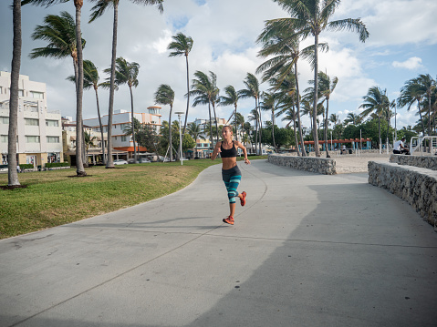 Sportive young woman jogging outdoors, Miami Beach. People body conscious and heathy lifestyle concept.