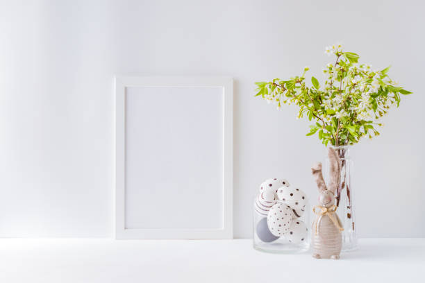 istock Home interior with easter decor. Mockup with a white frame and spring flowers in a vases on a light background 1208172548