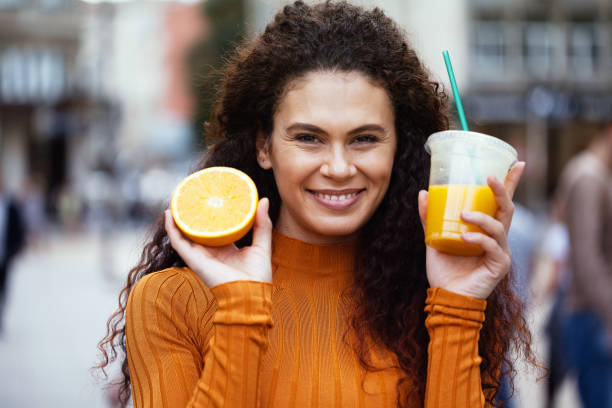 istock Beautiful young woman drinking orange juice 1208181226
