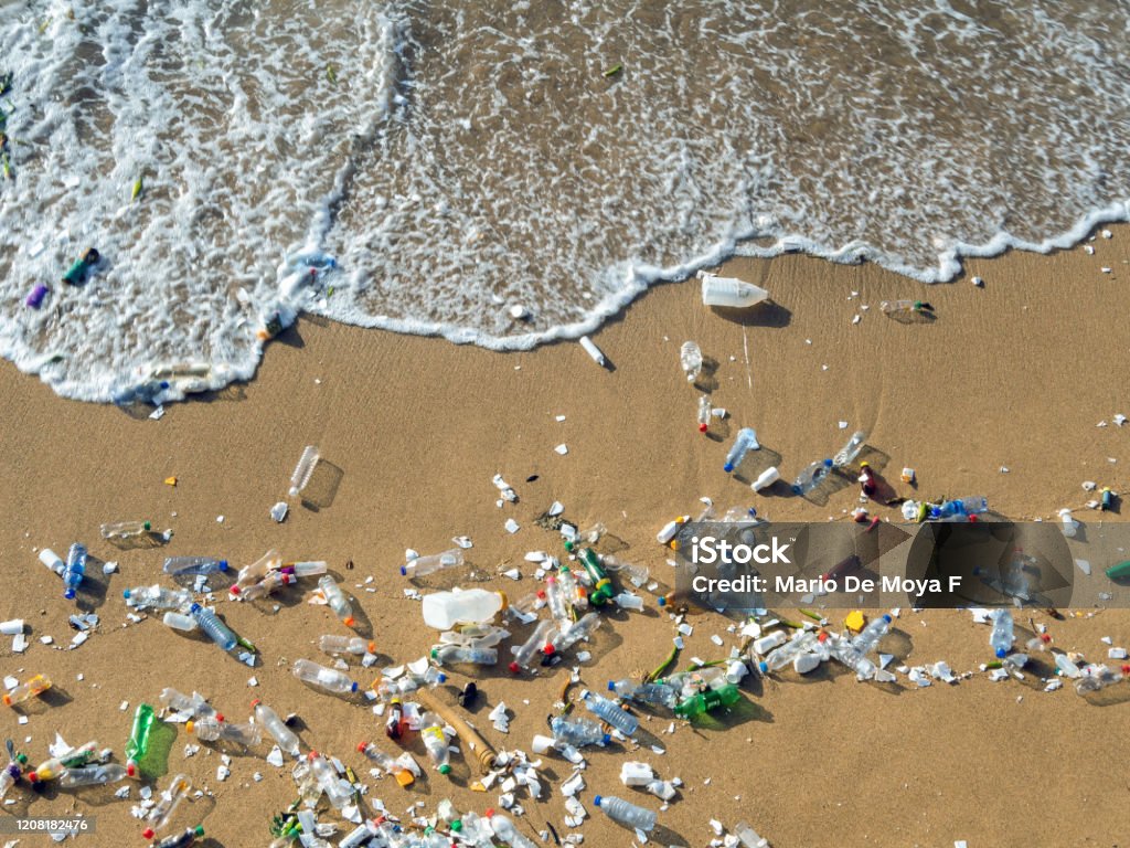 Waves pushing plastic waste to the beach Plastic waste polluting the beach, mostly bottles that are pushed and attracted to the waves Plastic Stock Photo