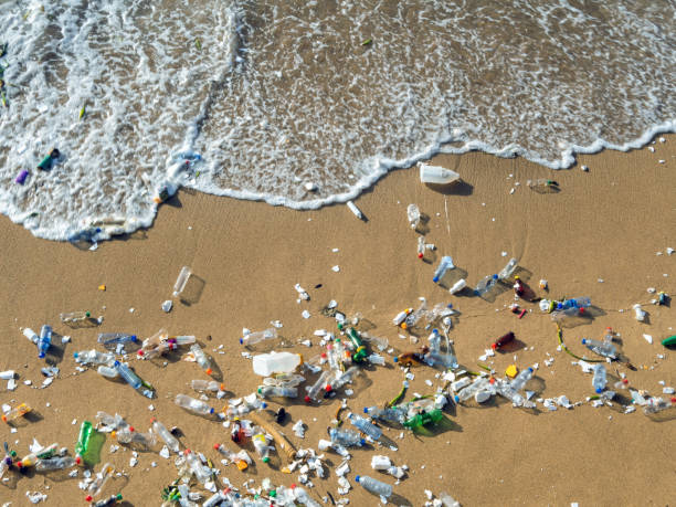 Waves pushing plastic waste to the beach Plastic waste polluting the beach, mostly bottles that are pushed and attracted to the waves rubbish dump stock pictures, royalty-free photos & images