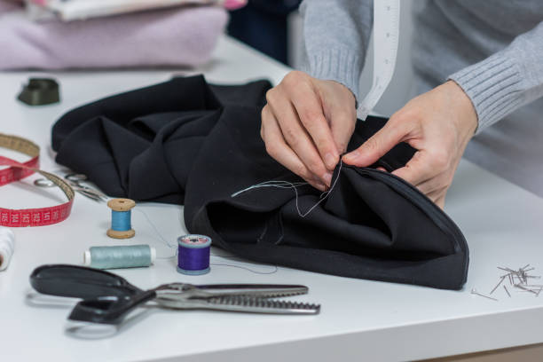 istock Seamstress is stitching zipper to black wide-leg pants 1208182889