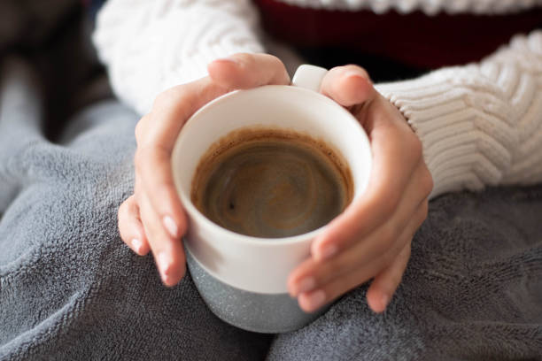 istock Woman sitting on bed and holding cup 1208182985