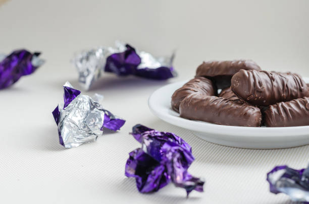 White saucer with sweets. Around the labels from eaten sweets. Sweet tooth or sweets lover. Selective focus.